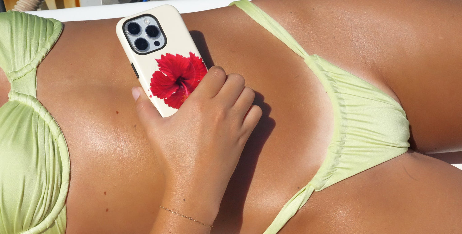 Person wearing a green bikini holding a phone with a red flower case on a bright background